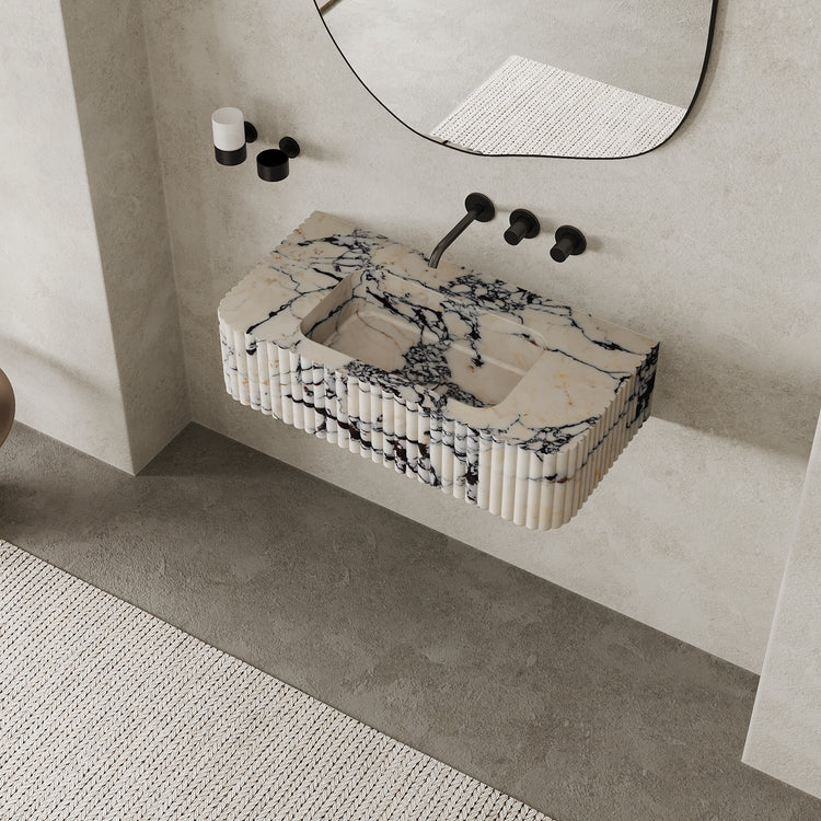 Raya Ribbed Marble Basin in Calacatta Viola mounted on wall in modern Scandinavian bathroom with round mirror and black faucets